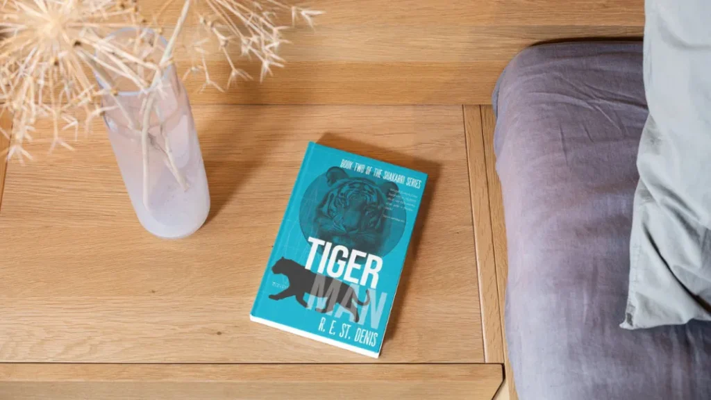 A hardcover book in blue titled Tiger Man on an oak table
